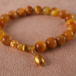 Close-up of 18K gold charm and Tiger Eye bead with polished Citrine stones