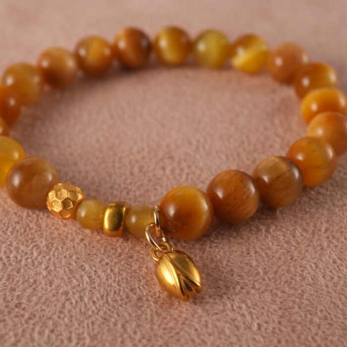 Close-up of 18K gold charm and Tiger Eye bead with polished Citrine stones