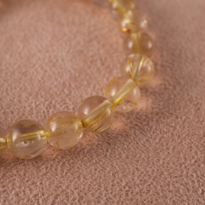 Close-up of golden threads inside rutilated quartz beads and butterfly charm