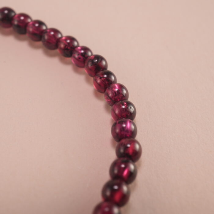 Close-up of garnet and pearl beads strung on elastic cord