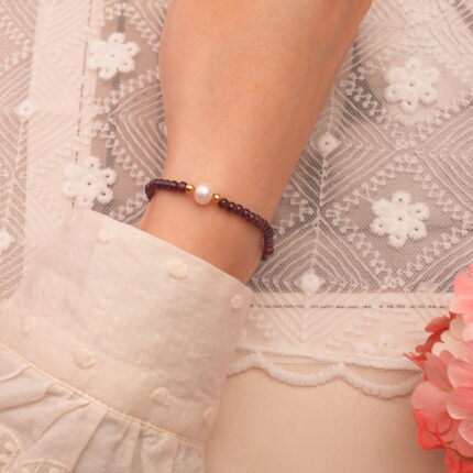 Garnet and pearl bracelet worn on wrist with minimalist outfit