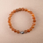 Peach Moonstone bracelet with silver fish charm, featuring soft 6mm beads