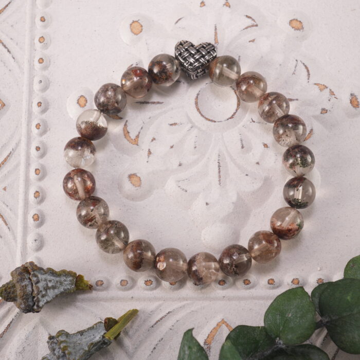 Bracelet resting gently beside the green leaf in natural sunlight, evoking warmth and calm