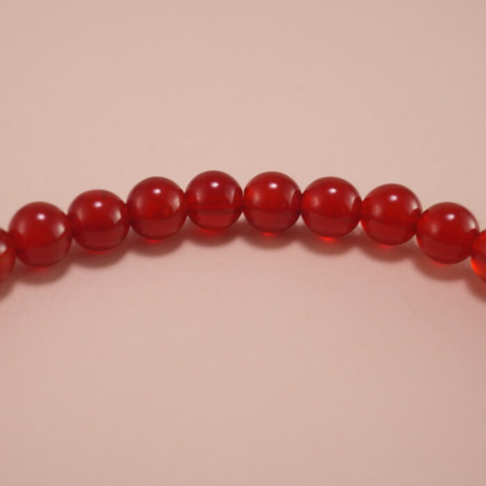 Close-up of red agate beads and silver butterfly charm on 4mm bracelet