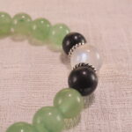 Close-up of 8mm beads: light green Prehnite, luminous Moonstone, and speckled Obsidian