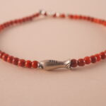 Close-up of fine red agate beads and silver on minimalist bracelet