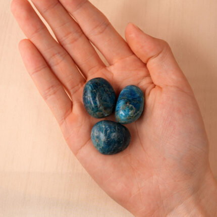 Hand holding Natural Blue Apatite Tumbled Stone from polished stone set showing texture and color