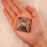 Person holding a Natural Crazy Agate Pyramid Decoration, showcasing its unique patterns and vibrant colors.