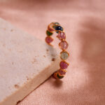Tourmaline Woven Ring showcasing calming greens, pinks, and energizing reds, with a woven band design symbolizing strength