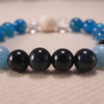 Close-up of blue apatite, obsidian, and quartz bracelet with lava stone.