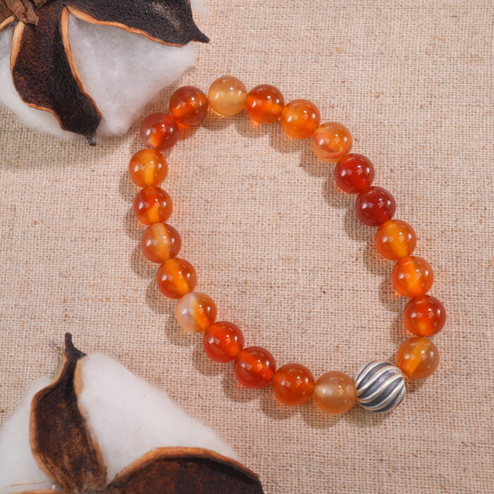 Flatlay of flower red agate bracelet arranged with props.