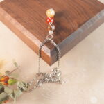 Leo zodiac necklace with tiger eye, red jasper, and citrine displayed on wooden board.