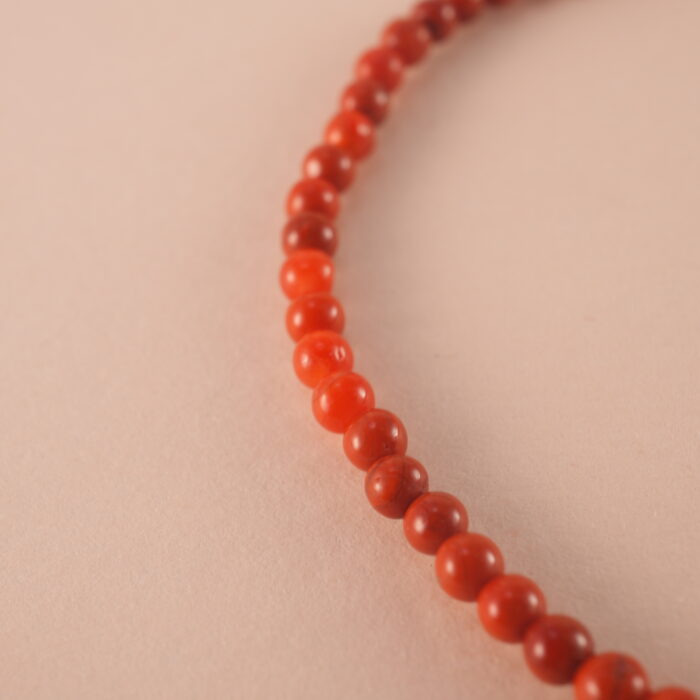Close-up of red agate bracelet with smooth beads and deep red color.