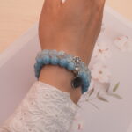 Model wearing blue chalcedony and aquamarine bracelets stacked together.