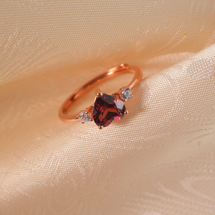 Close-up view of the heart-cut garnet and rose gold band, showing the fine polish and setting.