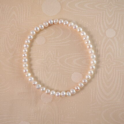 A lustrous pearl stretch bracelet laid flat on a white background, highlighting its classic and elegant design.